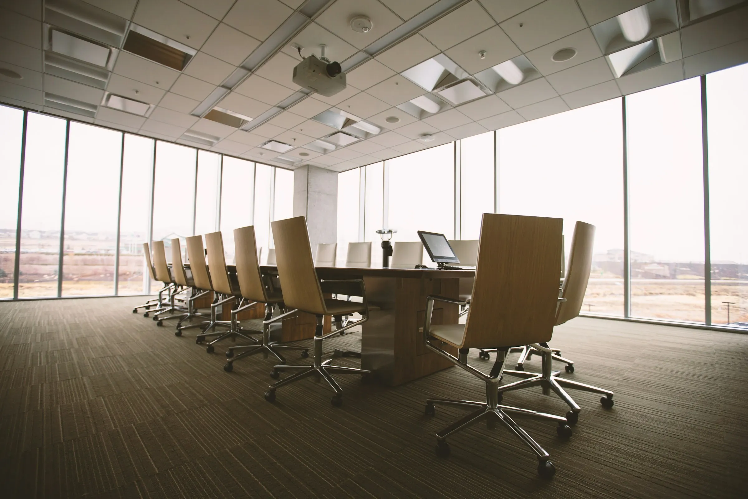 A bright, minimalist boardroom with a timber table and city views