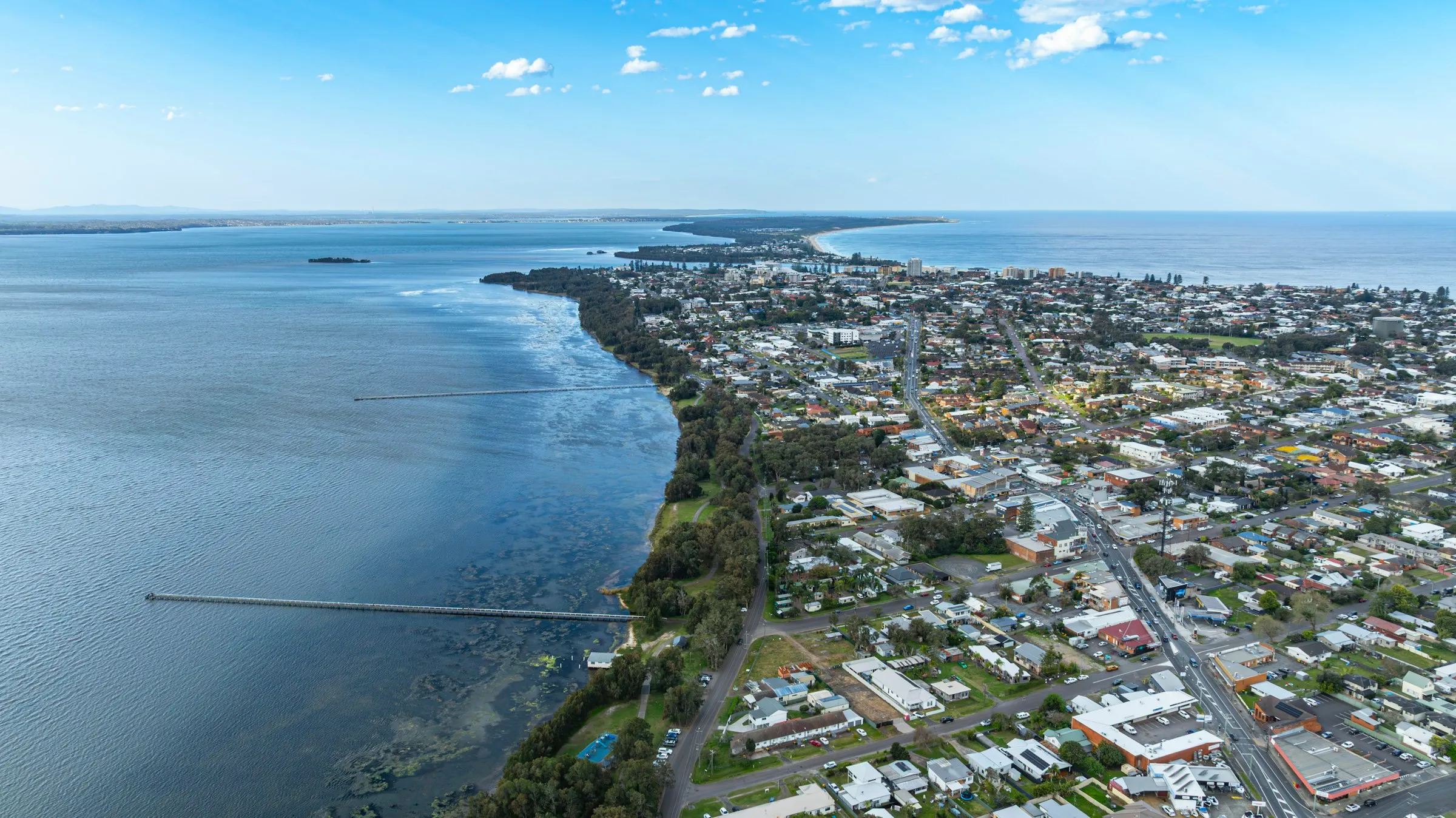 Aerial view of a sunny coastal suburb between the lake and the ocean on the NSW Central Coast