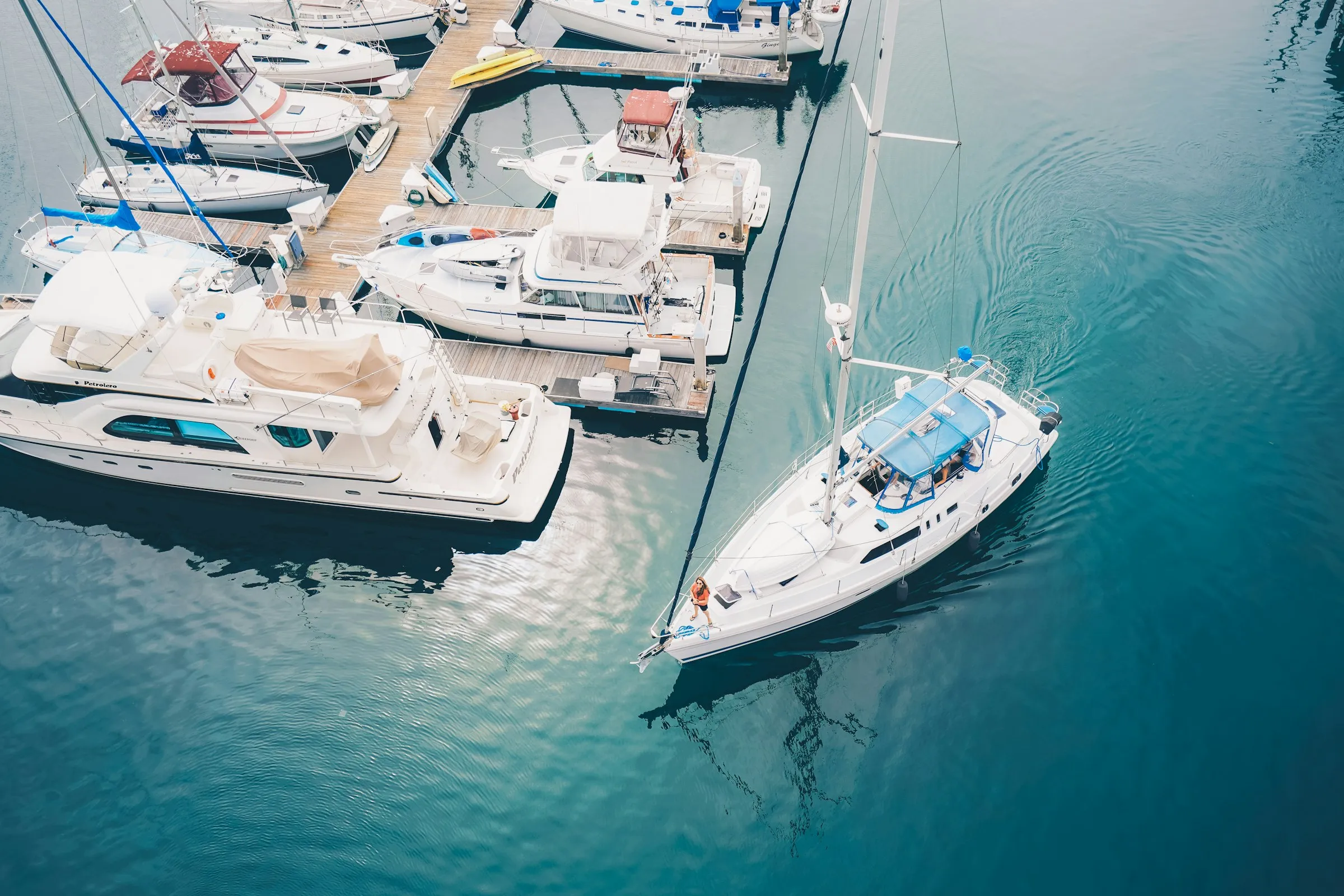 Aerial view of yachts in a sunny marina with clear turquoise water